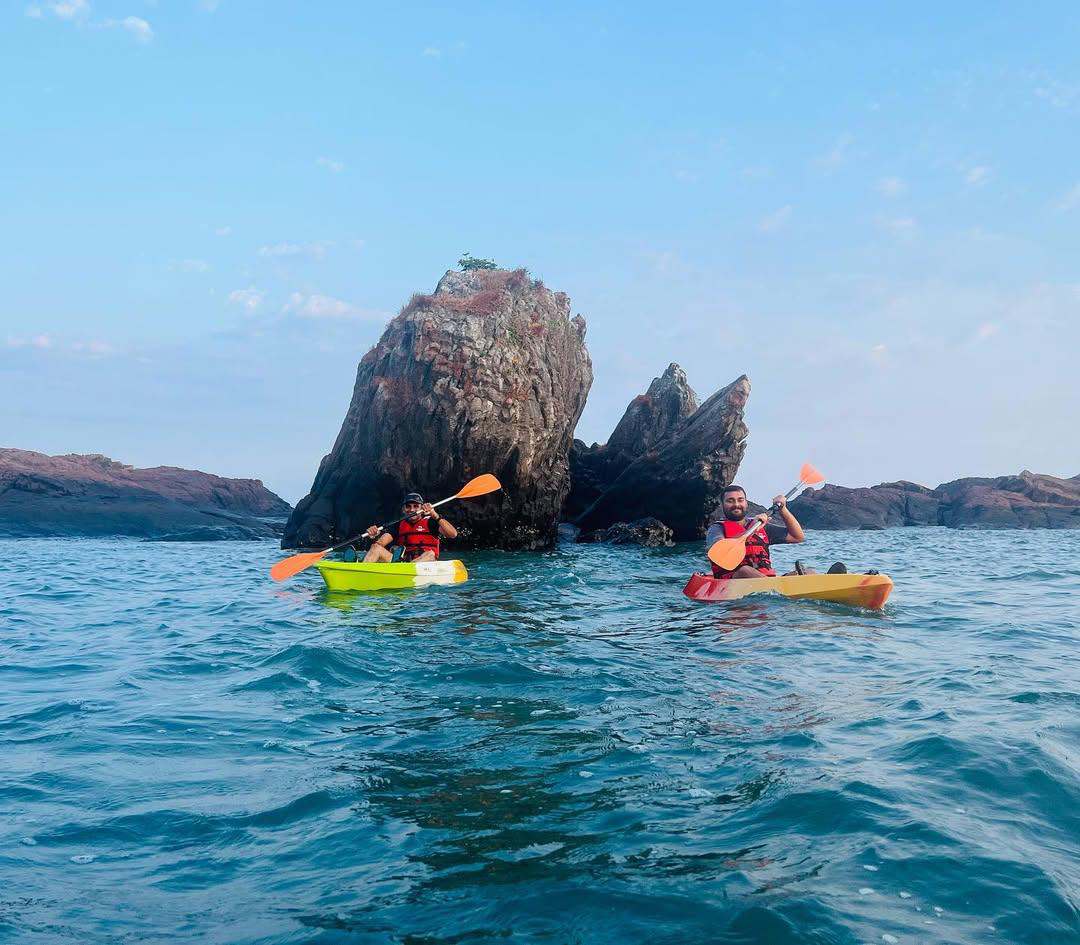 Two sea kayaks paddling past a rugged rocky coastline